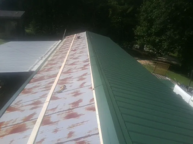 Old rusted panels beside newly installed green metal roofing — Wind Damage Roof Repair by Roofing Brothers in Burlington